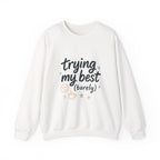 White cozy crewneck sweatshirt with "trying my best (barely)" hand-lettering, sleepy smiley, stars, and steaming mug design