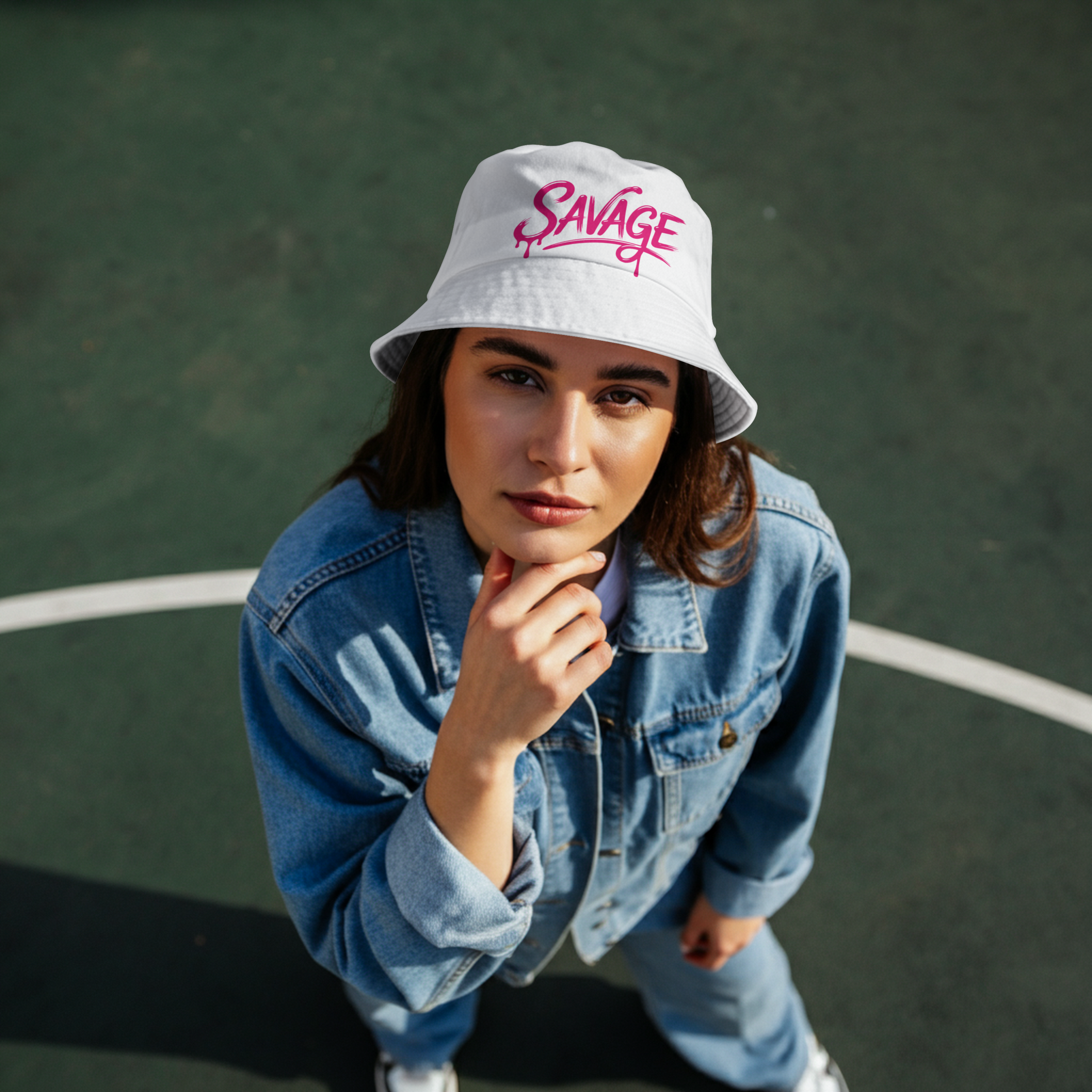 Young woman wearing white Savage Embroidered Bucket Hat with pink script on a tennis court
